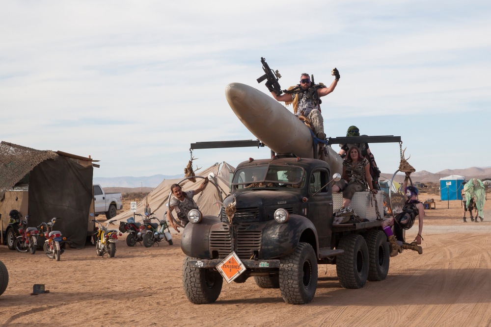 dystopian landscape outside the bitcoin citadel. man with goggles sitting on rocket loaded on rugged truck 