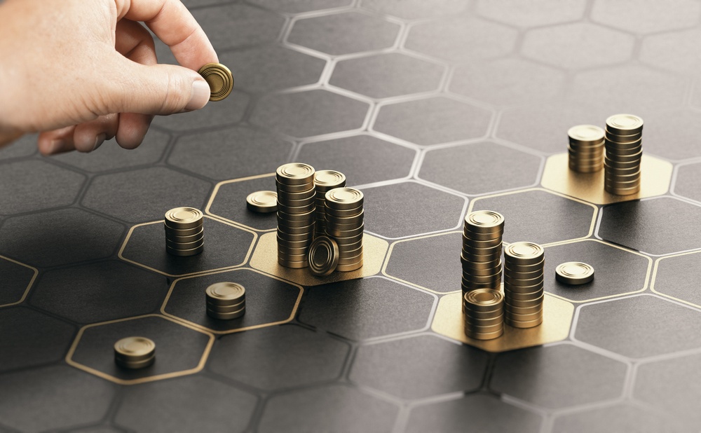 choosing investments represented by hand stacking coins on gold and black honeycomb grid 