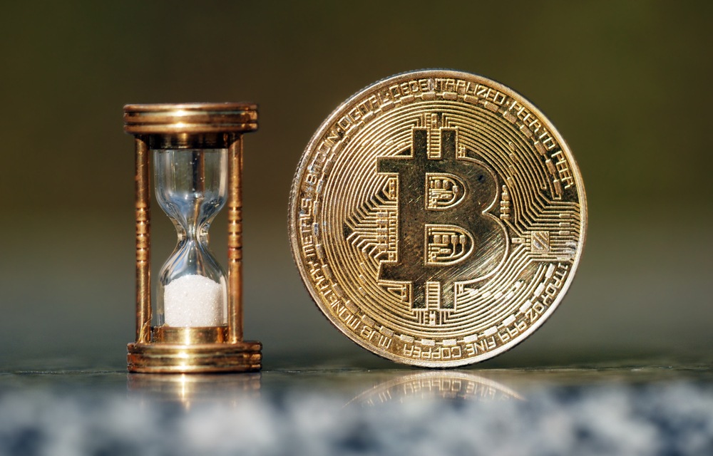 Is it too late to buy bitcoin?golden bitcoin coin sitting next to miniature copper and glass hourglass that has run out of time 