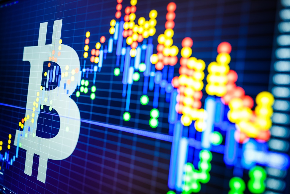 bitcoin stocks price chart. A close up image of a computer screen showing a B symbol for bitcoin and a price graph that is going up and down over time. 