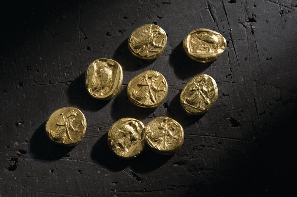 8 thick gold Lydian coins on black stone background 