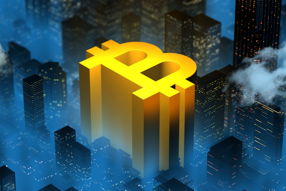 Is Bitcoin a company? Yellow bitcoin logo appearing to emerge from the city foggy night city skyline as a corporate building 