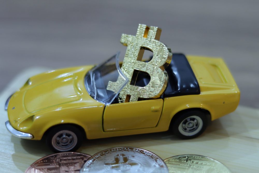 yellow toy car corvette with bitcoin symbol sitting inside the vehicle 