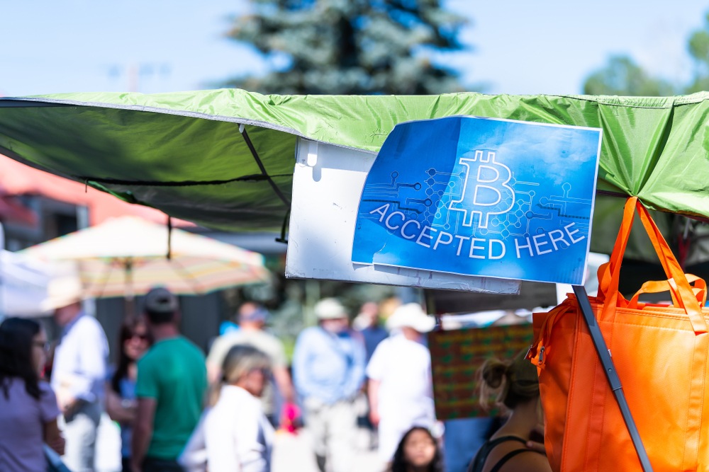 farmers market temporary tent with blue printed sign  "bitcoin accepted here"