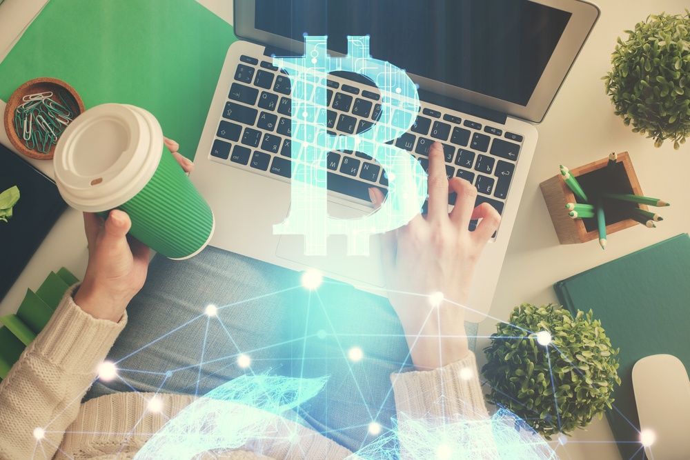 earn sats working. woman working on a laptop with green paper coffee cup earning bitcoin (sats) for work 