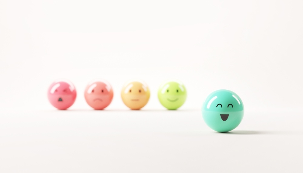 rating system of colored balls with facial expressions. Green face with happiest face in foreground with others blurred in background 