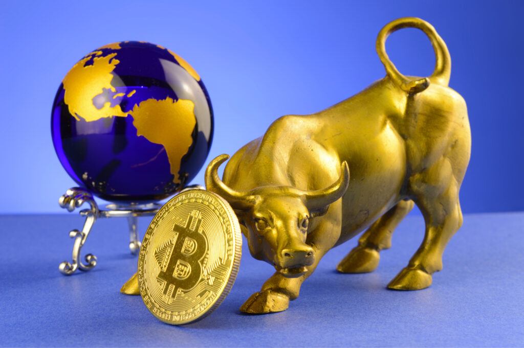 gold bull sculpted from metal with translucent blue and gold globe in background. bitcoin bull price jump. 