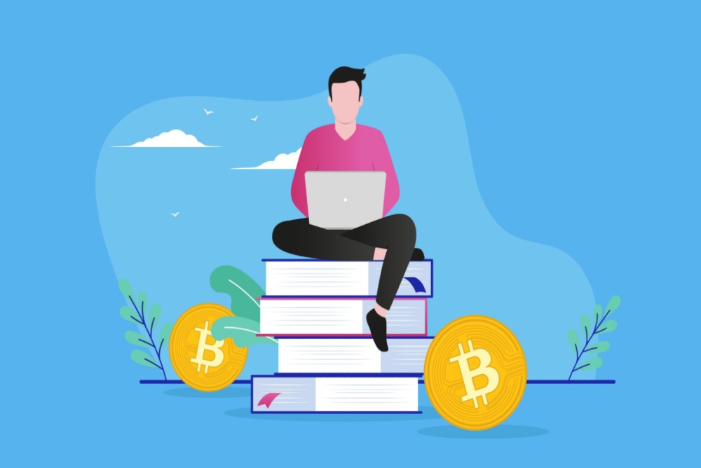 young man on laptop learning about bitcoin sitting on a stack of books 