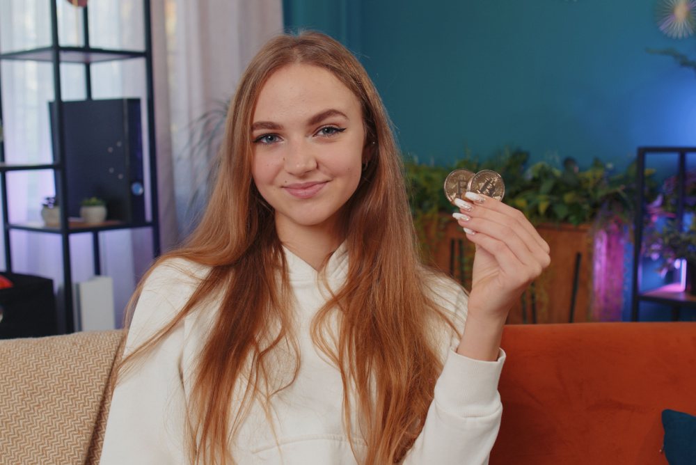 zoomer girl holding two bitcoins. younger generation saving money in bitcoin, not gold. 